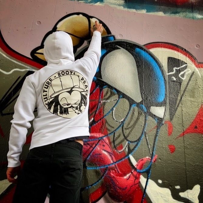 Artist in a Dready hoodie painting a mural