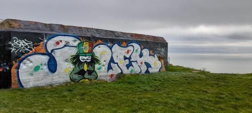 Dready mural on a bunker under a cloudy sky